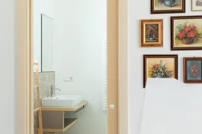 a bathroom with a sink and paintings on the wall at DOMUS FABER in Merano