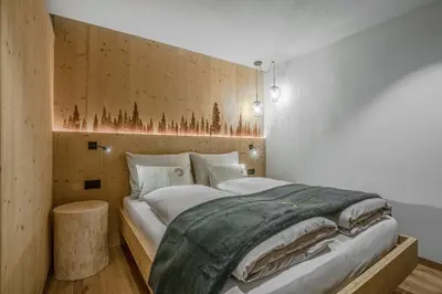 a bedroom with a large bed with a wooden wall at Bio Lüch Ruances in San Cassiano