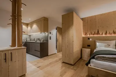 a bedroom with wooden cabinets and a bed and a kitchen at Bio Lüch Ruances in San Cassiano
