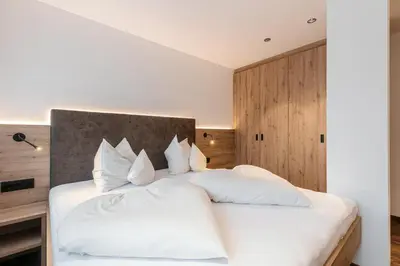 a bedroom with a white bed with white pillows at Alpenrose Alpine Living in Selva