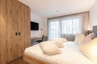 a bedroom with a white bed with a wooden cabinet at Alpenrose Alpine Living in Selva