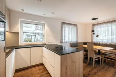 a kitchen with white cabinets and a table with chairs at Alpenrose Alpine Living in Selva
