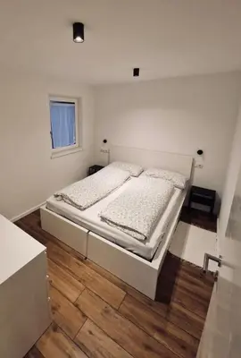 a bedroom with a white bed and a wooden floor at M&M-Apartment in Brunico