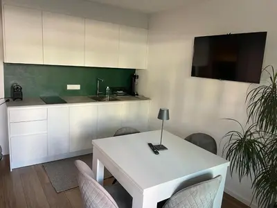 a kitchen with a white table with chairs and a tv at M&M-Apartment in Brunico