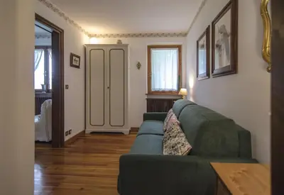 a living room with a green couch and a window at Cà Mughi Studio in Zuel