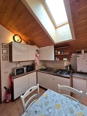 a kitchen with a table and a skylight at Appartamento Latemar Predazzo in Predazzo