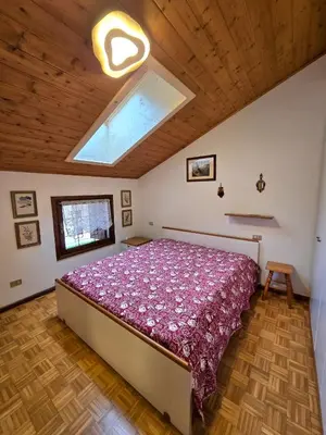a bedroom with a bed in a room with a skylight at Appartamento Latemar Predazzo in Predazzo