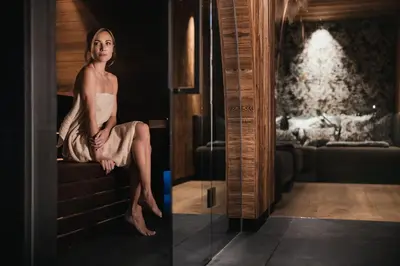 a woman in a dress sitting on a couch at Luxury Spa Chalet Lum d'Or in Selva di Val Gardena