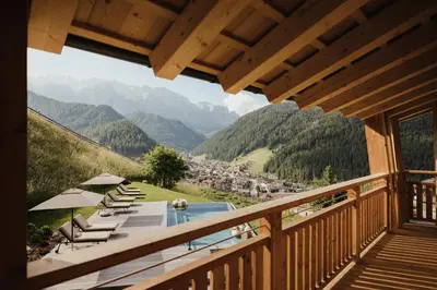 a balcony with chairs and a pool and mountains at Luxury Spa Chalet Lum d'Or in Selva di Val Gardena