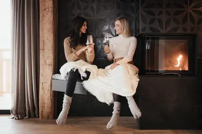 two women sitting on a couch with glasses of champagne at Luxury Spa Chalet Lum d'Or in Selva di Val Gardena