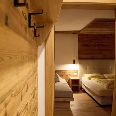 a bedroom with two beds in a room with wooden walls at GSCNARA - APARTMENT LIN in Antermoia