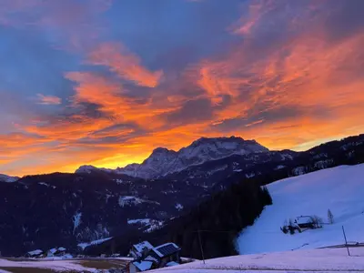 a sunset over a snow covered mountain with a lake at GSCNARA - APARTMENT LIN in Antermoia