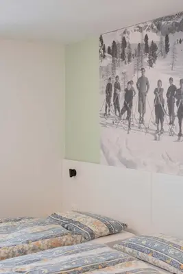 two beds in a room with a painting on the wall at Francesca's home in Pozza di Fassa