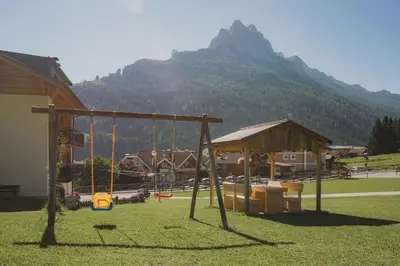 a playground with a swing and a mountain in the background at Francesca's home in Pozza di Fassa
