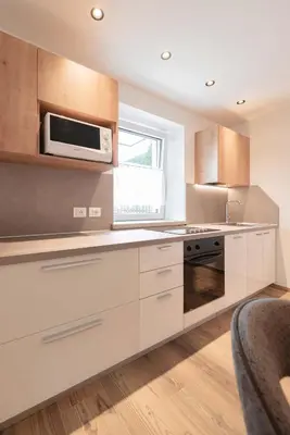 a kitchen with white cabinets and a microwave at Francesca's home in Pozza di Fassa