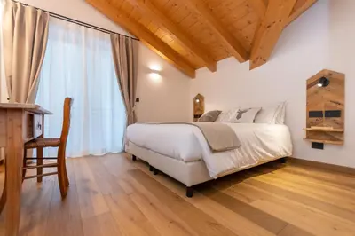a bedroom with a large bed and a wooden floor at B&B El Lares - B&B L'Avez in Canale dʼAgordo
