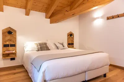 a bedroom with a large white bed with wooden ceilings at B&B El Lares - B&B L'Avez in Canale dʼAgordo