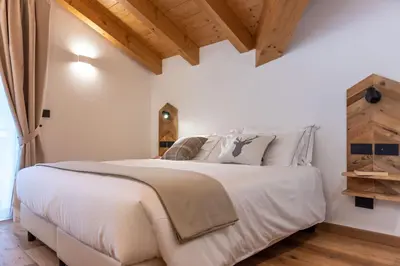 a bedroom with a large white bed and wooden ceilings at B&B El Lares - B&B L'Avez in Canale dʼAgordo