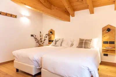 two beds in a bedroom with wooden ceilings at B&B El Lares - B&B L'Avez in Canale dʼAgordo
