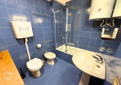 a blue tiled bathroom with a toilet and a sink at Hometoday - Appartamento nel cuore di San Vito di Cadore in San Vito di Cadore