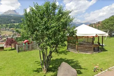 a tree in a field with a gazebo at Ciasa Gran Panorama Moena in Moena