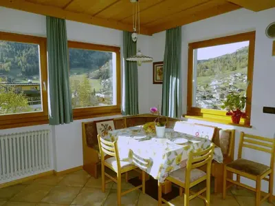 a dining room with a table and chairs and windows at Ciasa Gran Panorama Moena in Moena