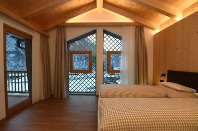 a bedroom with two beds and a large window at Les Ciases Chalets Dolomites in San Vigilio Di Marebbe
