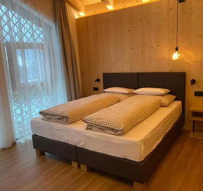 a bedroom with two beds and a large window at Les Ciases Chalets Dolomites in San Vigilio Di Marebbe