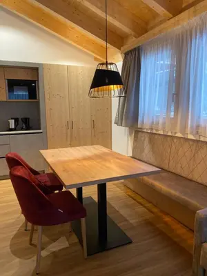 a dining room with a wooden table and a red chair at Les Ciases Chalets Dolomites in San Vigilio Di Marebbe