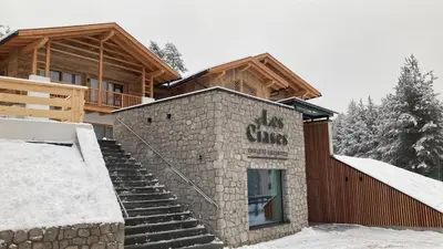 a building with a sign that reads the guys at Les Ciases Chalets Dolomites in San Vigilio Di Marebbe