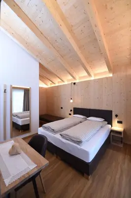 a bedroom with two beds and a wooden ceiling at Les Ciases Chalets Dolomites in San Vigilio Di Marebbe