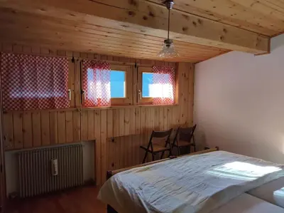 a bedroom with a bed and two chairs in it at Falcade Dolomiti La Quiete Mansarda panoramica in Fregona