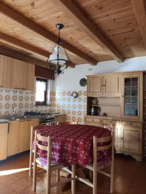 a kitchen with a table and wooden cabinets at Falcade Dolomiti La Quiete Mansarda panoramica in Fregona
