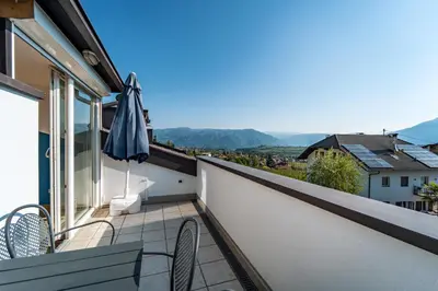a balcony with two chairs and an umbrella at Mias Apartments - #MiasEppan#Badl in Appiano sulla Strada del Vino