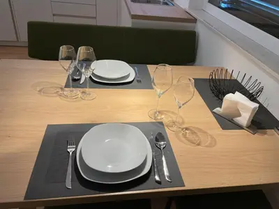 a wooden table with plates and wine glasses on it at Apartments Johanna in Nalles