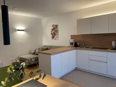 a kitchen with white cabinets and a living room at Apartments Johanna in Nalles