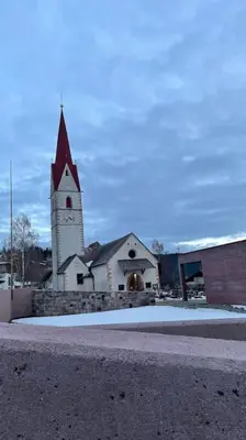 a church with a steeple and a building with snow at Living Apartment Larcher in Verano