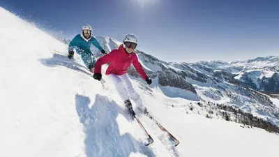 two people are skiing down a snow covered mountain at PredazzoHouse in Predazzo