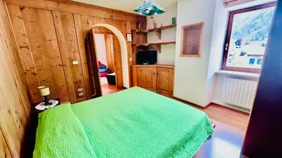 a bedroom with a green bed and a window at PredazzoHouse in Predazzo