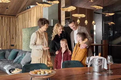 a family standing around a table in a living room at Luxury Chalet Vilaiet in Ortisei