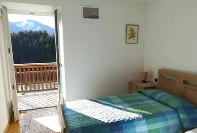 a bedroom with a bed and a view of a mountain at Appartamento Flora in Tesero