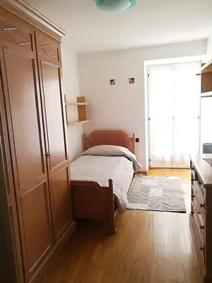 a bedroom with a bed and a large cabinet at Appartamento Flora in Tesero
