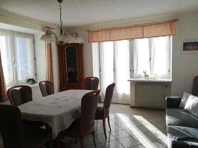 a dining room with a table and chairs and a couch at Appartamento Flora in Tesero