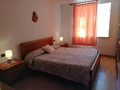 a bedroom with a bed and two lamps and a window at Appartamento Flora in Tesero