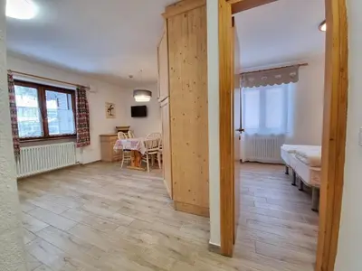 a hallway with a bedroom and a dining room with a table at Fraines in Alba di Canazei