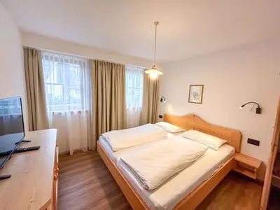 a bedroom with a bed and a flat screen tv at Appartements ai Sanc in Corvara in Badia