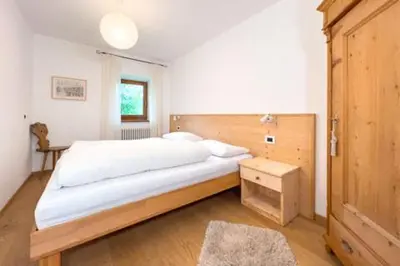 a bedroom with a large bed with a wooden headboard at Appartements ai Sanc in Corvara in Badia