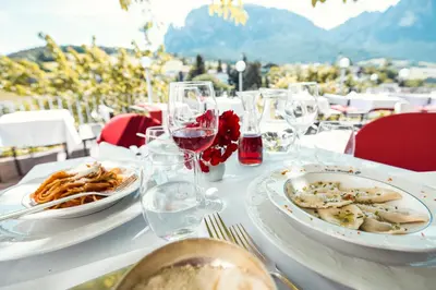 a white table with plates of food and wine glasses at Hotel Rose Wenzer in Vols am Schlern