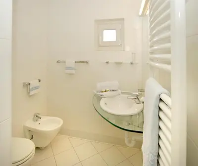a white bathroom with a sink and a toilet at Hotel Rose Wenzer in Vols am Schlern