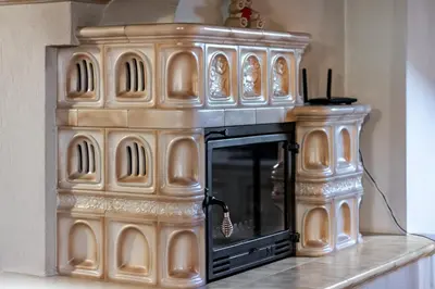 a wooden fireplace in a kitchen with a stove at DolomiApartments - Casa Margherita in Predazzo